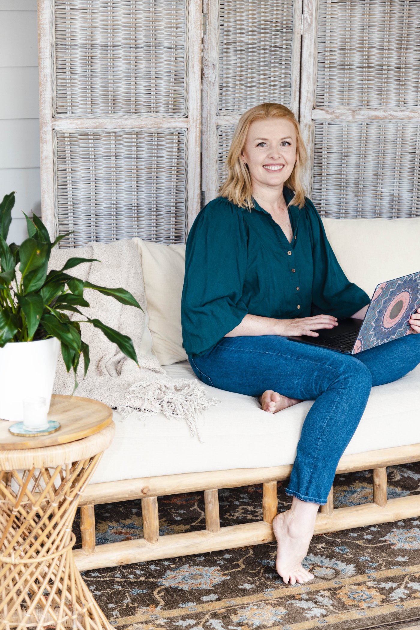 Fionna sitting on a daybed with her laptop, smiling