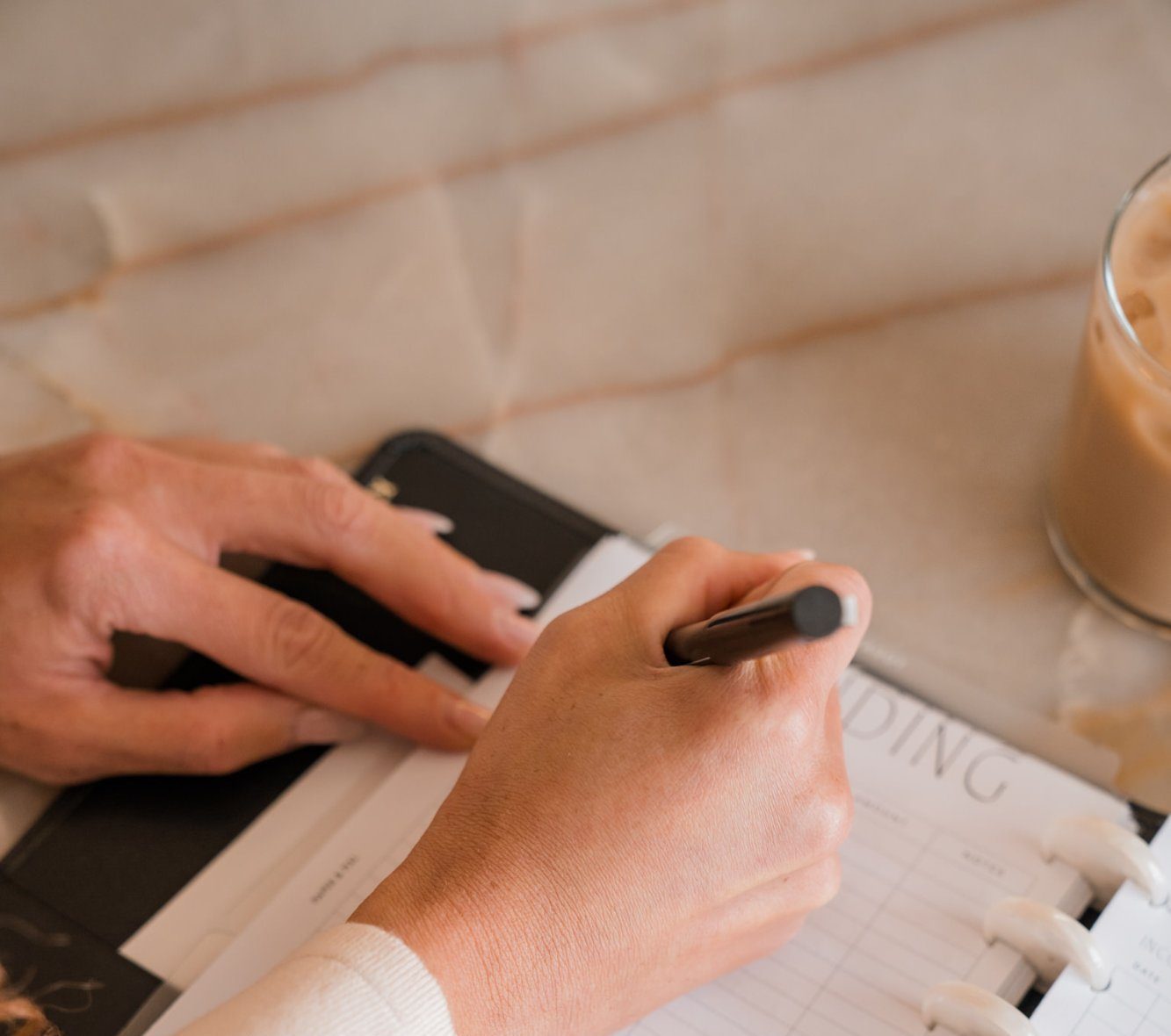 Hands writing in a notebook with a pen