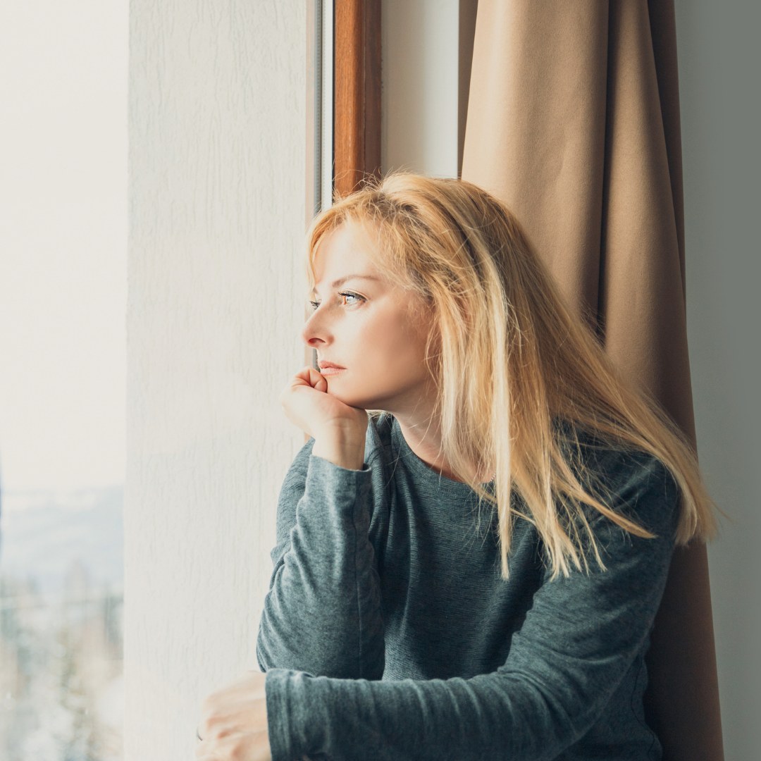 A woman gazing out a window, lost in thought