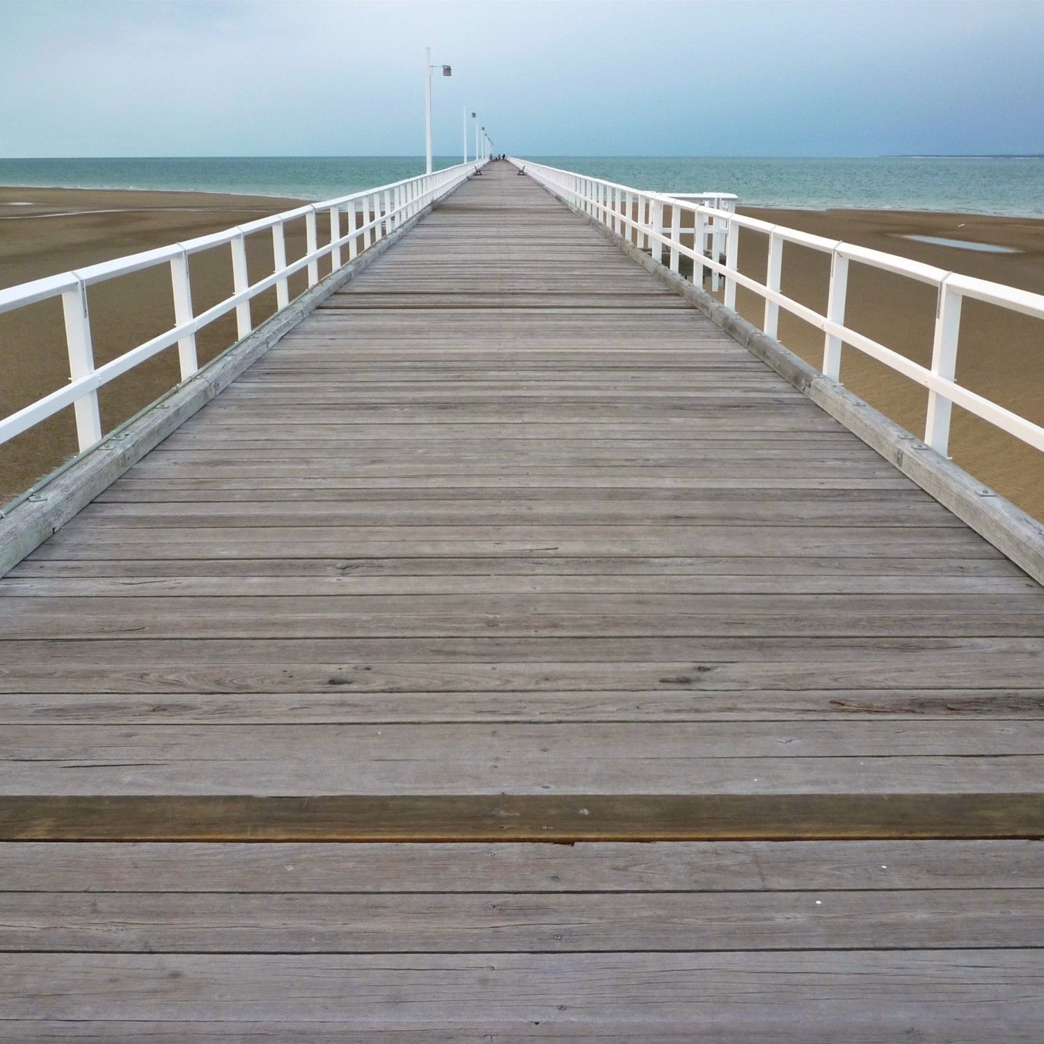 The long timber boardwalk of Urangan Pier reaching out over the water at Hervey Bay